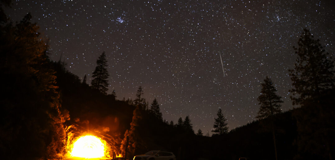 A view shows the Geminids meteor shower streaking across the night sky as stargazers gather at the Valley View of Yosemite National Park in California