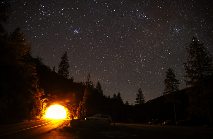 A view shows the Geminids meteor shower streaking across the night sky as stargazers gather at the Valley View of Yosemite National Park in California