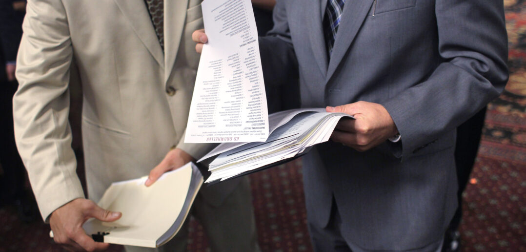 An employer (R), looks over the resume of an unemployed man at a career fair