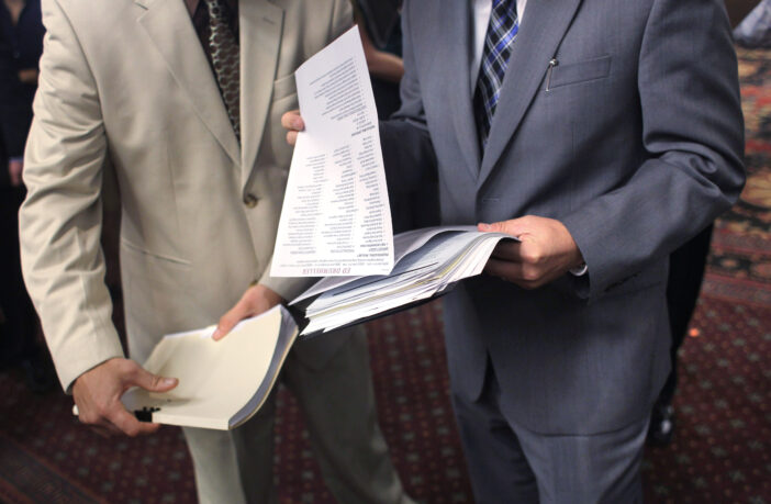An employer (R), looks over the resume of an unemployed man at a career fair